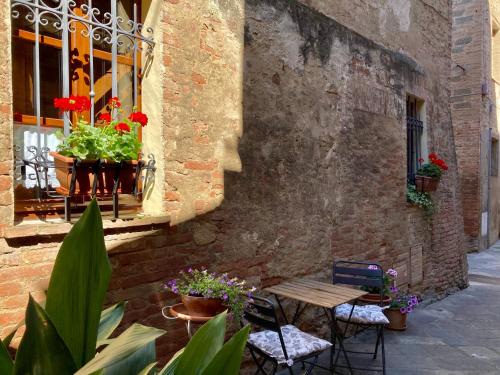patio z drewnianym stołem, krzesłami i kwiatami w obiekcie La Casina w mieście Buonconvento