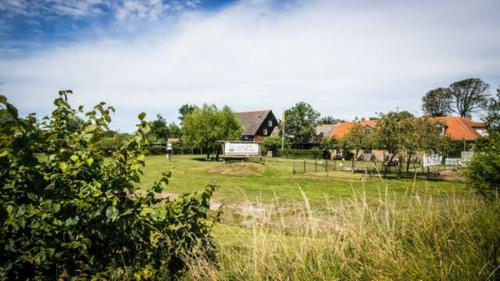 un champ avec une maison en arrière-plan dans l'établissement Holidayhome - Kon Emmaweg 26 - Vrouwenpolder - Uitspanning Oranjezon, à Vrouwenpolder