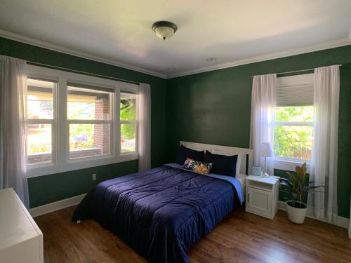 ein grünes Schlafzimmer mit einem Bett und zwei Fenstern in der Unterkunft Private Room in West Highlands House in Denver