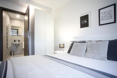 een slaapkamer met een bed met witte lakens en kussens bij Imperium Rooms Zagreb Airport in Velika Gorica