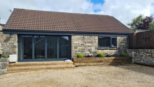 a stone house with a large sliding glass window at The Studio in Farmborough