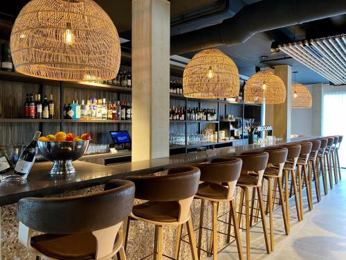 a bar with a row of chairs and lights at Hotel Zeeuws Licht I Kloeg Collection in Dishoek