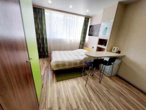 um pequeno quarto com uma cama, uma mesa e cadeiras em Апартаменты СВ "Атлант" 2 em Tver