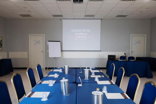 a conference room with blue tables and chairs and a screen at Grand Hotel Salerno in Salerno