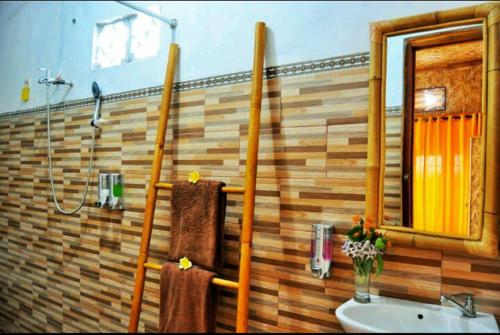 ein Badezimmer mit einem Waschbecken, einem Spiegel und Handtüchern in der Unterkunft Gentari Homestay and Tour in Nusa Penida