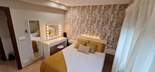 a bedroom with a bed with yellow pillows and a mirror at CASA CAXOTA: Planta baja con terraza y vistas al mar in Fisterra