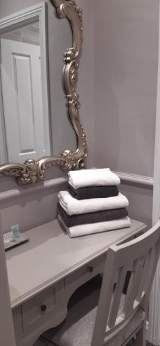 una pila de toallas en una mesa frente a un espejo en Arkle House, en Pennyburn