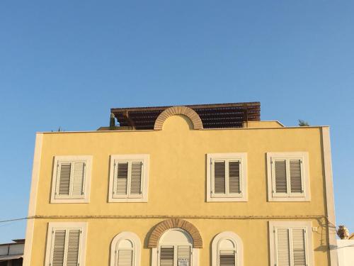 a yellow building with white windows and a blue sky at Attico sul Porto Vecchio - Lampedusa in Lampedusa