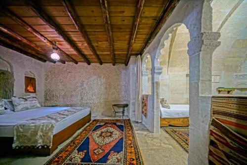 a bedroom with a bed and a room with a rug at Elysee Cave House in Goreme