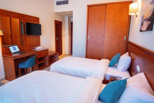 a hotel room with two beds and a desk at Lamar Azur Hotel in Dumyāţ al Jadīdah