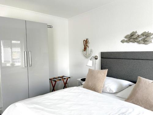 Westerstrasse 6 في بوسوم: غرفة نوم بيضاء مع سرير وخزانة