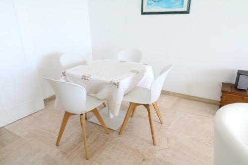 - une table à manger blanche avec des chaises blanches dans l'établissement Amazing sea view 2 bedroom beach front 303, à Cannes