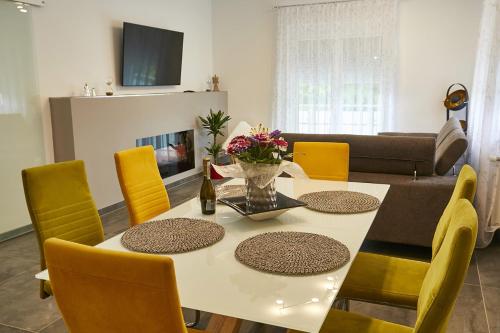 a dining room with a white table and yellow chairs at Seeblick Susanne in Schiefling am See