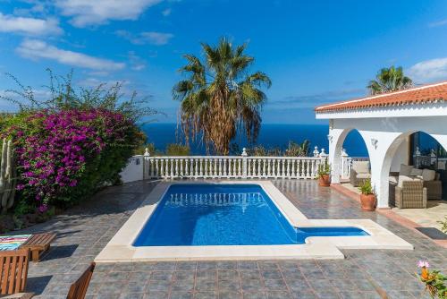 una piscina frente a una casa con el océano en Villa Marina, en Sauzal