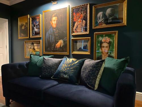 a living room with a blue couch and a bunch of paintings at Apartment 'Boho' in Yeovil
