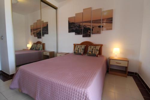 アルヴォルにあるApartamentoSolPraia - AMOREIRASのベッドルーム1室(ピンクベッド1台、ナイトスタンド2台付)