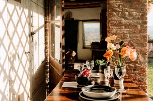 a table with plates and glasses and flowers on it at CASA ANGIOLINA - Casa vacanze con vista sulle colline in Govone