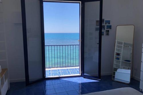 a room with a view of the ocean through a glass door at Il mare in un bicchiere in Sciacca