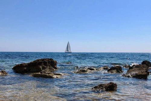 a sail boat in the ocean with rocks in the water at Il mare in un bicchiere in Sciacca
