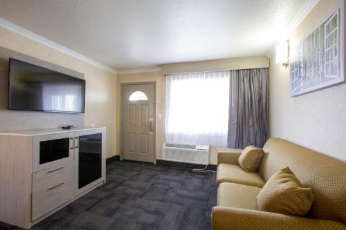a living room with a couch and a flat screen tv at Hotel Aspen Flagstaff/ Grand Canyon InnSuites in Flagstaff