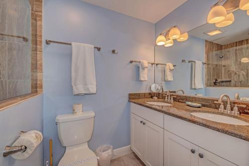 a bathroom with a toilet and two sinks and a mirror at Salt Air East by Beach Retreats in Holmes Beach