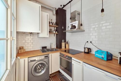 パリにあるCosy Apartment for 2 People near Pigalleの白いキャビネットと洗濯機付きのキッチン