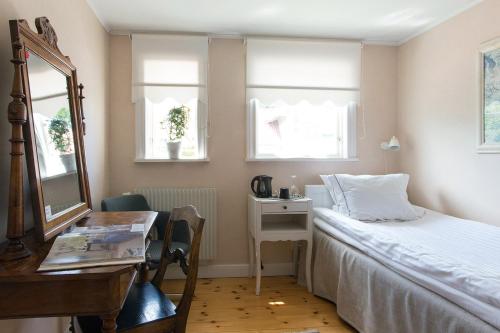a bedroom with a bed and a desk and a mirror at Hotell Villa Vesta in Ronneby