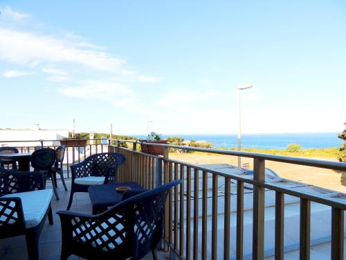 a balcony with chairs and tables and the ocean at Hotel Porto Badisco in Porto Badisco