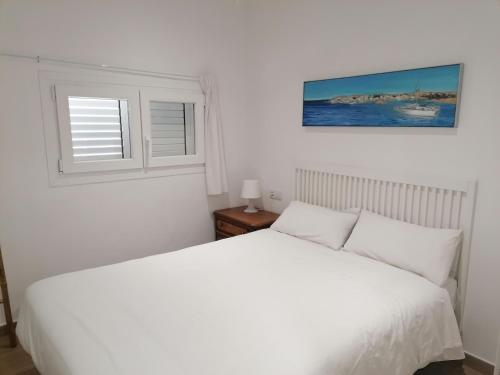 een slaapkamer met een wit bed en een raam bij Old Side Duplex Platja d'Aro in Platja  d'Aro