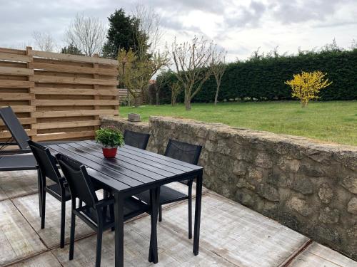 a table and chairs on a patio with a stone wall at les gites du grand saule in Tardinghen