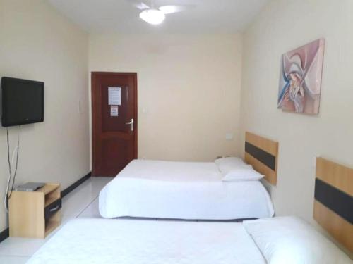 twee bedden in een kamer met een tv en een bed sidx sidx sidx bij Gv Park Hotel in Governador Valadares