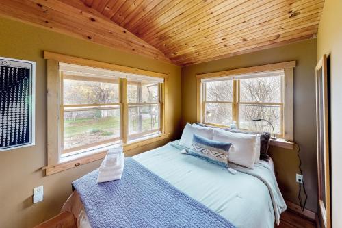 a small bedroom with a bed and two windows at VT Guest Cottage in Moretown