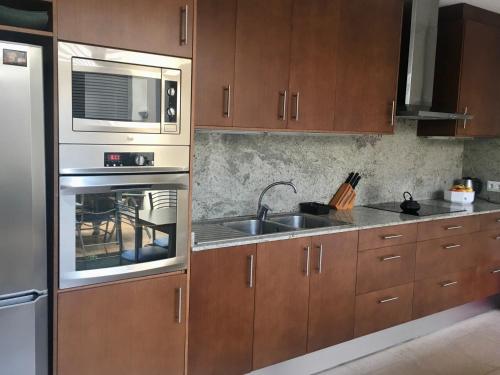 a kitchen with wooden cabinets and a sink and a microwave at Casa de pueblo amplia in Sa Pobla