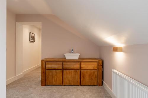 uma casa de banho com uma cómoda de madeira num sótão em The Hawthorn Rooms Dingle em Dingle