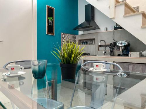 uma mesa de vidro numa cozinha com uma parede azul em Diomede Rooms - Manfredi Homes&Villas em Manfredonia