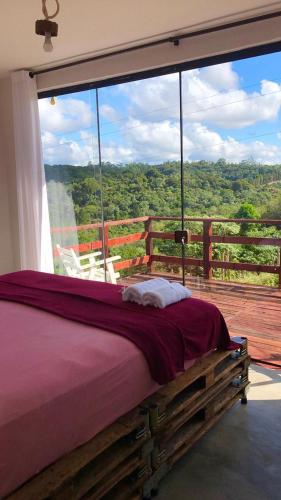 a bedroom with a bed in front of a large window at Atma Anna in Piedade