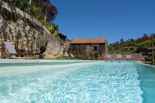a swimming pool with a house in the background at Casa da Gueira in Vale de Cambra