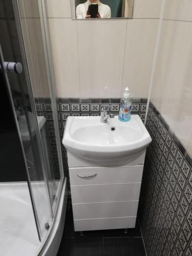 a bathroom with a sink and a shower and a person taking a picture at Ленина 31 in Omsk