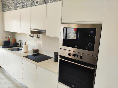 eine Küche mit weißen Schränken und einer schwarzen Mikrowelle in der Unterkunft Apartamento Rooftop Montenegro in Faro