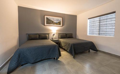 a bedroom with two beds and a window at Hotel Nuve Gomez Palacio in Gómez Palacio