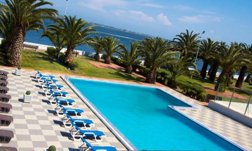 - une vue sur la piscine bordée de chaises et de palmiers dans l'établissement Riabela Inn, à Torreira
