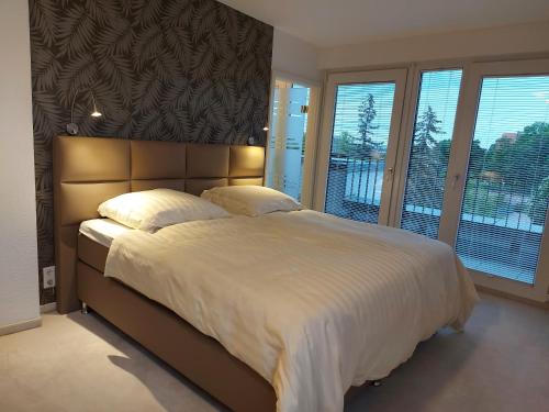 Schlafzimmer mit einem großen Bett mit weißer Bettwäsche und Fenstern in der Unterkunft AT THE TOP - Penthouse über den Dächern der Stadt in Erfurt
