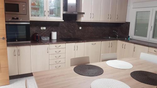 a kitchen with white cabinets and a wooden table at Apartamento MARIÑA SANXENXO in Sanxenxo