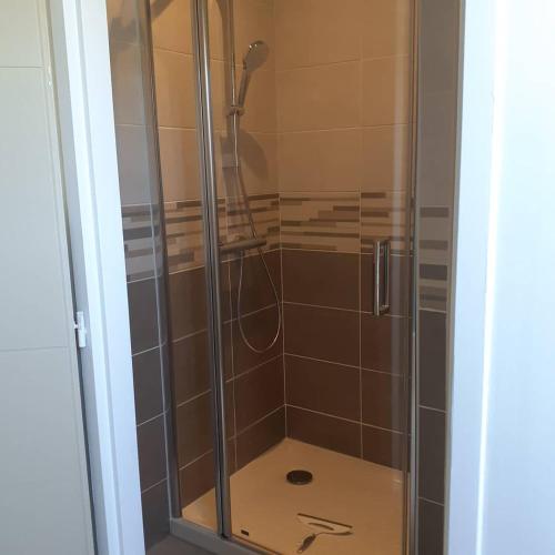 une douche avec une porte vitrée dans une salle de bain dans l'établissement Appartement à la campagne, à Noyal-Muzillac