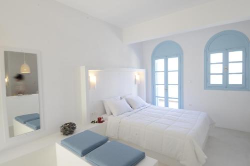 ein weißes Schlafzimmer mit einem Bett und einem Spiegel in der Unterkunft Villa Maria Rooms in Akrotiri