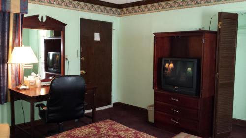 Habitación de hotel con escritorio, TV y dormitorio. en Executive Lodge, en Alcoa