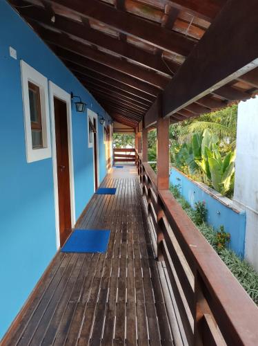 a wooden boardwalk leading to a house with a blue wall at Pousada Vistazul - Pé na Areia in Bertioga