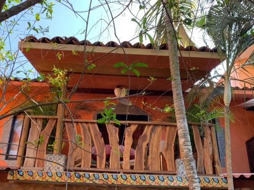 a house with a wooden balcony with palm trees at Hotel Casamar Suites in Puerto Escondido