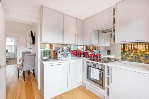 cocina blanca con armarios blancos y mesa en Lovely 1-Bed Apartment in London, en Londres