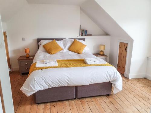 a bedroom with a large bed with yellow pillows at Sea Otter Cottage in Appin